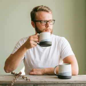 Modern minimalist porcelain mug held by a man at table